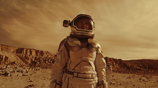 Tracking shot of woman in spacesuit looking around and searching for base location while exploring Mars with colleague