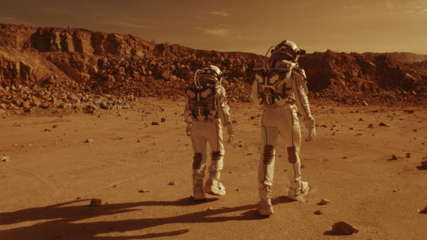 Unrecognizable astronauts walking on Mars Tracking shot of anonymous people in spacesuits walking on arid ground together during colonization of Mars real time stock pictures, royalty-free photos & images