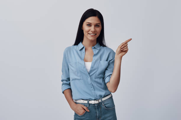 istock Attractive young woman looking at camera and pointing copy space 1324685329