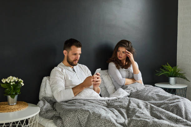 istock Man neglecting his girlfriend and using his mobile phone in bed 1324688168