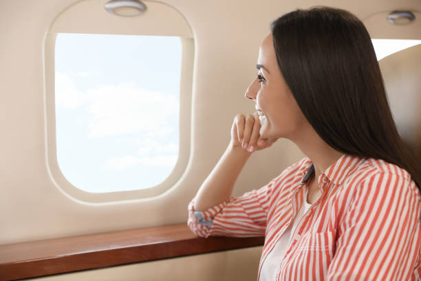 istock Young woman looking out window in airplane during flight 1324691835