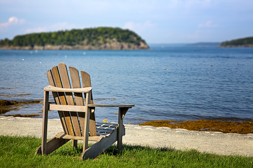 Selective focus on a  lone deck chair overlooking the water on a sunny day. Bar Harbor, Maine, USA