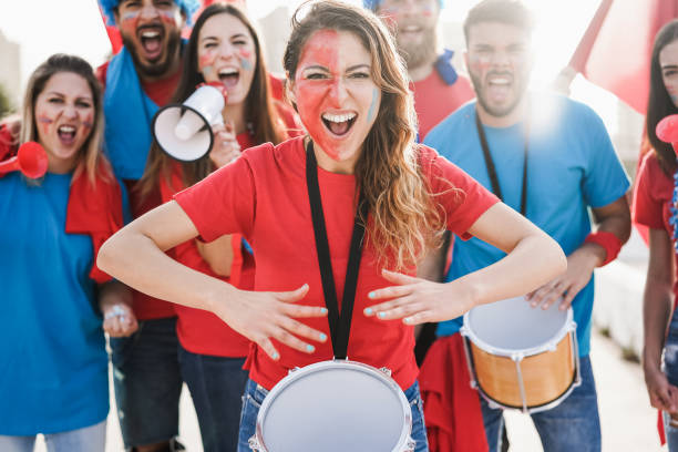 istock Crazy sport fans playing drums and screaming while supporting their team - Focus on center woman face 1324692976
