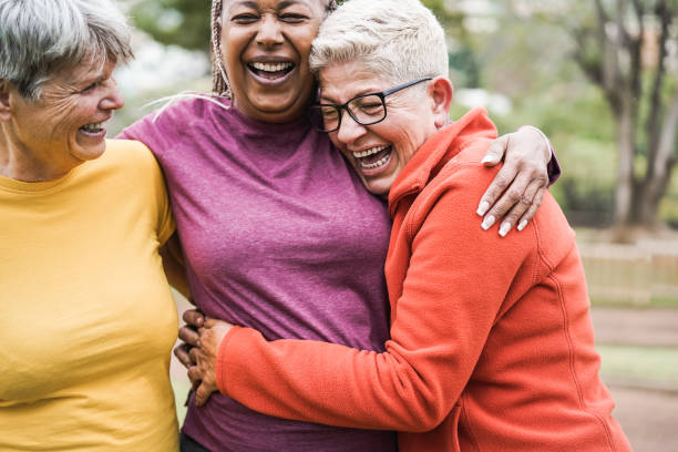 donne senior multirazziali che si divertono insieme dopo l'allenamento sportivo all'aperto - focus principale sul viso femminile destro - hiking senior adult exercising outdoors foto e immagini stock