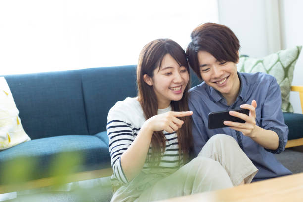 居間でリラックスした、見栄えの良い日本の男女 - couple sofa people heterosexual couple ストックフォトと画像