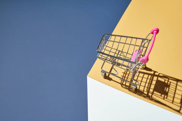 istock Shop trolley on yellow and blue bright background. Modern mall concept 1324694068