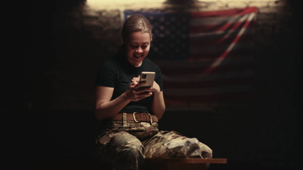istock Delighted female soldier sitting on bench and making video call 1324694489