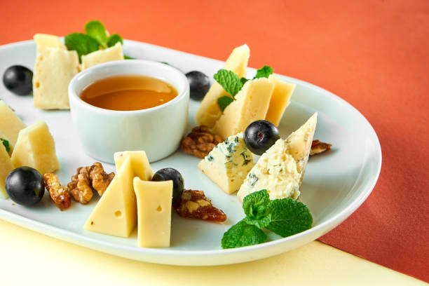 istock Appetizer - antipasti cheese plate with dorblu, parmesan and camembert, honey, nuts on bright colored backgrounds 1324696562