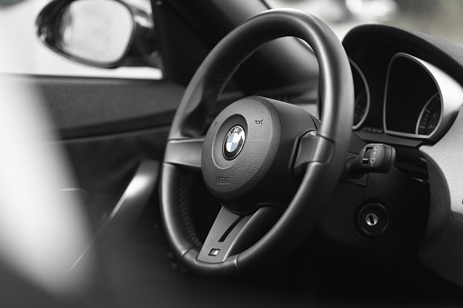Hamburg, Germany - June 20. 2021: close up of the Steering wheel from a modern BMW sports car cabriolet, parked somewhere in Hamburg. black and white shot