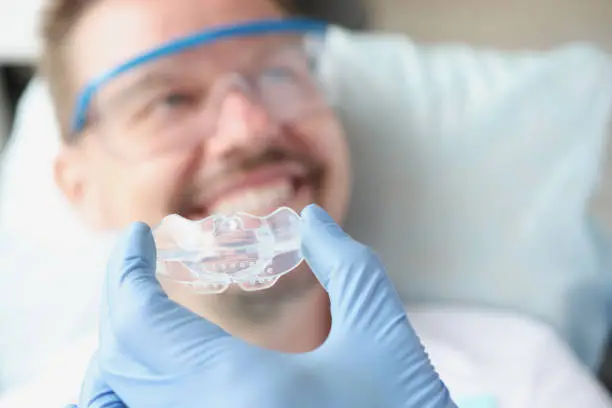 Dentist tries on silicone mouthguard to patient. Bite alignment in adults concept