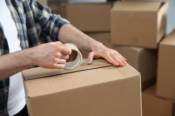 istock Man taping cardboard box indoors, closeup. Moving day 1324700084