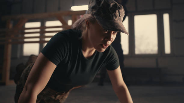Strong female soldier doing push up exercise on floor of grungy gym during workout on USA military base