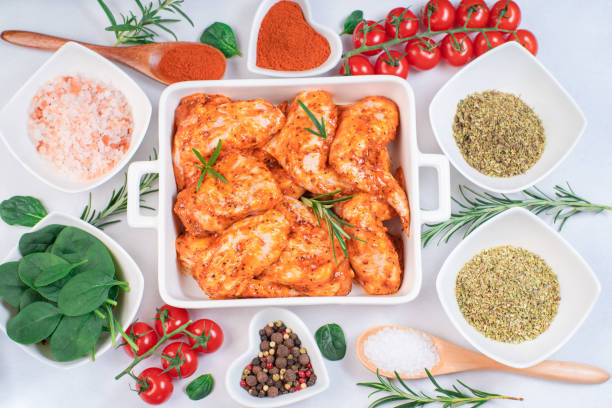Raw chicken wings.Marinated chicken wings on a baking plate with vegetables, tomatoes and spices.