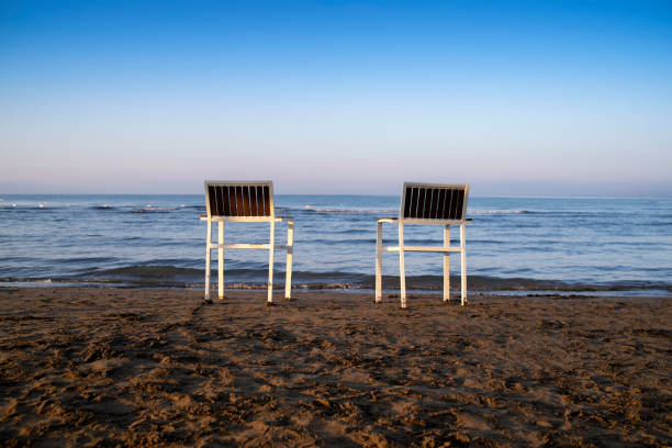 istock Chairs stand in the sand.Two empty chairs stand on beach in evening with view on marine sunset. 1324700867