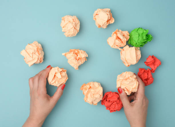 istock hand hold crumpled sheets of colored paper on a blue background. Solution concept, brainstorming 1324702075