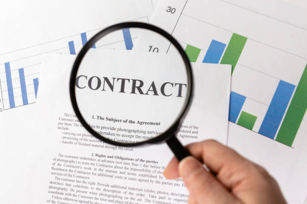 istock Businessman holding magnifying glass zoom and analyzing contract on chart background. 1324703368