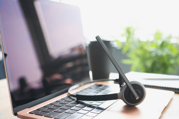 istock Headphones with microphone lying on laptop keyboard on desktop closeup 1324703809