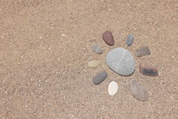 istock Stones lying on sand in shape of sun closeup background 1324703818