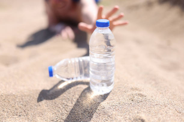 les mains masculines cherchent une bouteille d’eau en plastique en gros plan dans le désert - thirsty desert men reaching photos et images de collection