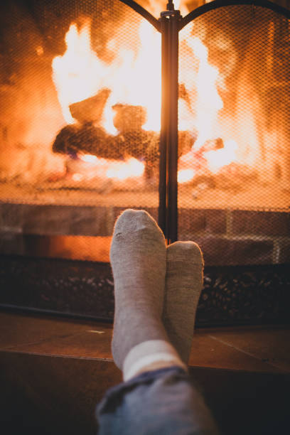 Close up feet in cozy warm socks near flames of fireplace. Close up feet in cozy warm socks near flames of fireplace. Fall or winter leasure. hygge photos stock pictures, royalty-free photos & images
