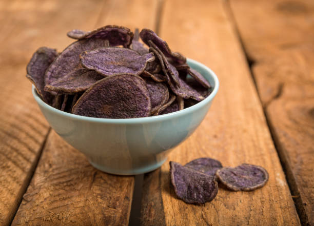 istock Potato chips made from purple potatoes in a bowl on rustic table 1324704250