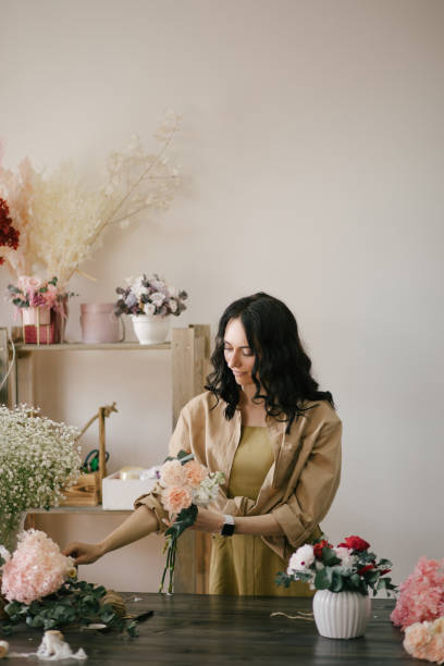 istock Young woman florist working in her flower studio, making beautiful bouquet using fresh plants and flowers. 1324704991