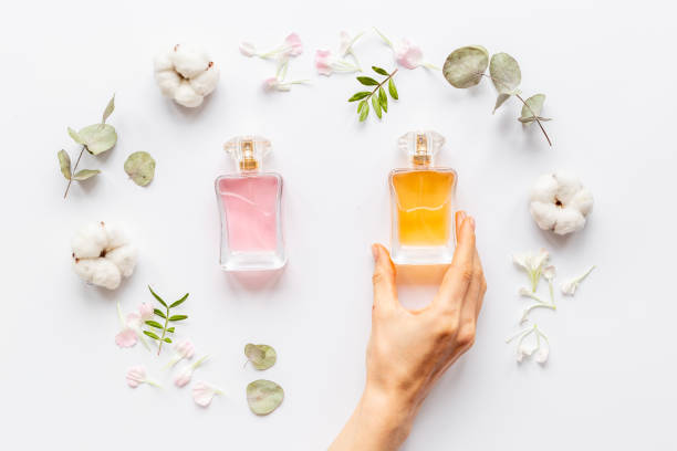 istock Hand holds perfume bottle with flowers flat lay 1324706709