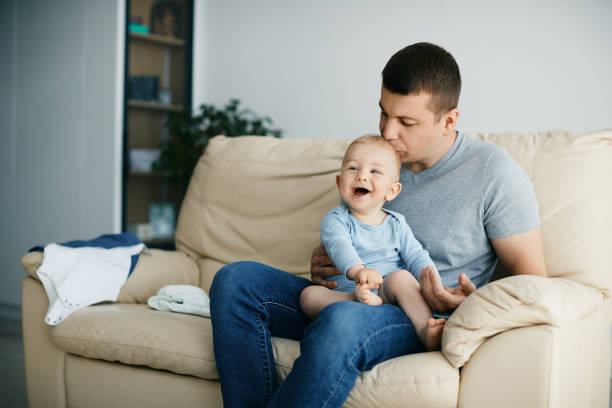 istock Joyful baby laughing while father is kissing him at home. 1324710019