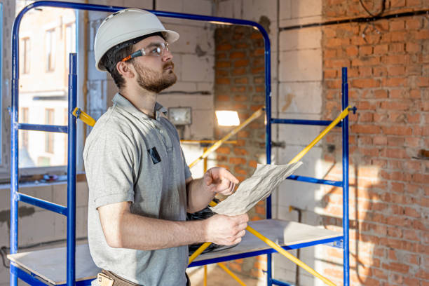 a handyman examines a drawing at a construction site. - protective workwear bricklayer manual worker construction imagens e fotografias de stock