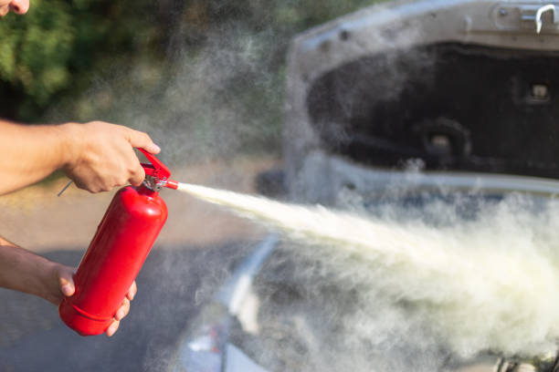 A man that use a fire extinguisher to turn off the fire from the car engine stock photo