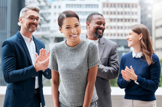 portrait d’une jeune femme d’affaires applaudie par son équipe - admiration photos et images de collection