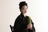白いスタジオの背景に孤立したポーズをとり、若い美しい日本人、国民の服装着物を着た女性の肖像。