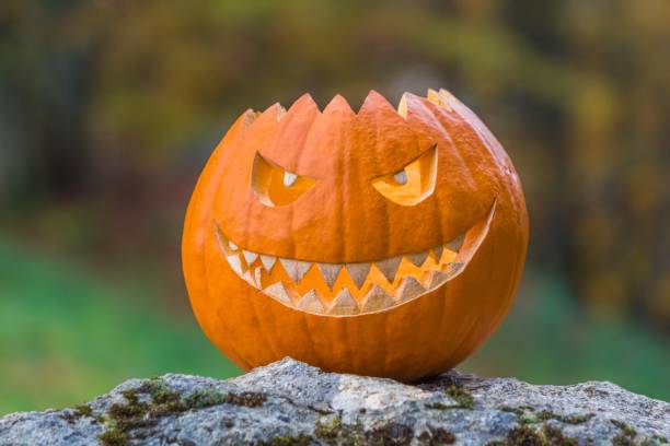 istock Scary smiling halloween pumpkin with nasty face on a stone 1324716133