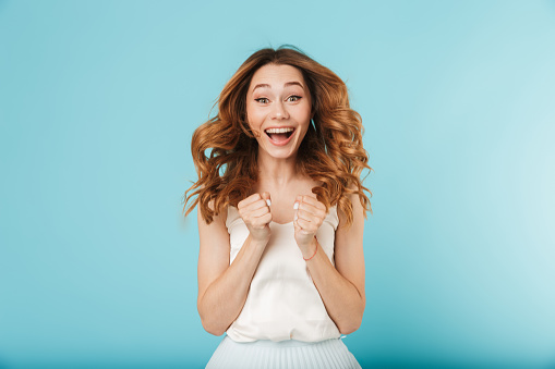 Image of young happy caucasian woman isolated over blue background looking camera.