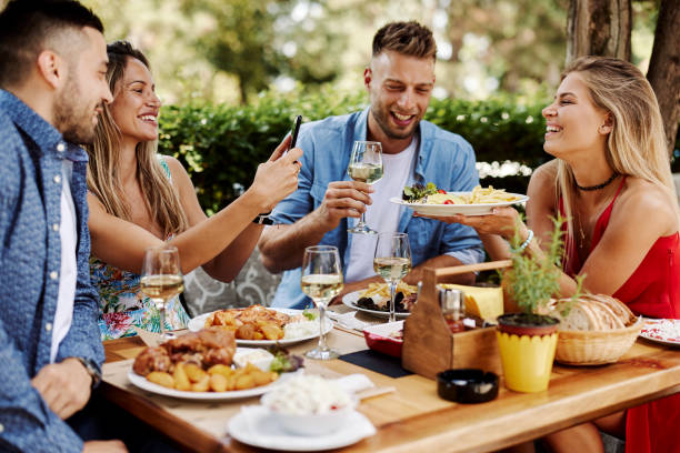 Groupe d’amis heureux déjeunant dans le restaurant pendant une journée d’été ensoleillée - Photo