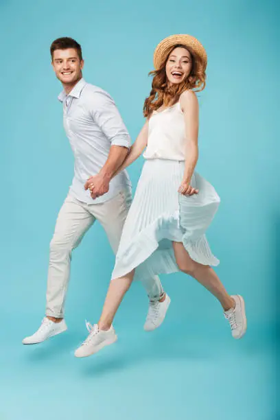 Image of young happy caucasian people man and woman jumping isolated over blue background.