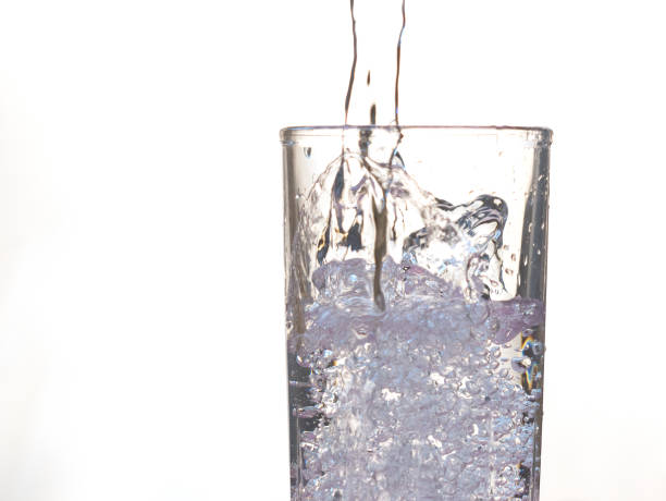 istock Water is poured into a glass. Transparent drinking water on a white background. Close-up. 1324720421