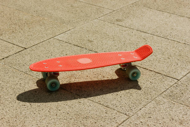 istock penny board on the asphalt. small plastic skateboard. pink penny Board with blue wheels 1324721515