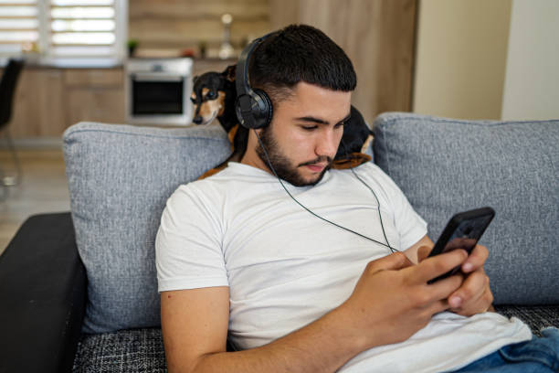 istock Young man using phone while hanging out with his dog pet 1324722095