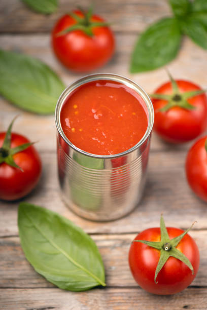 istock Open tin of tomatoes sauce with whole fresh tomatoes on a rustic wooden table 1324722167