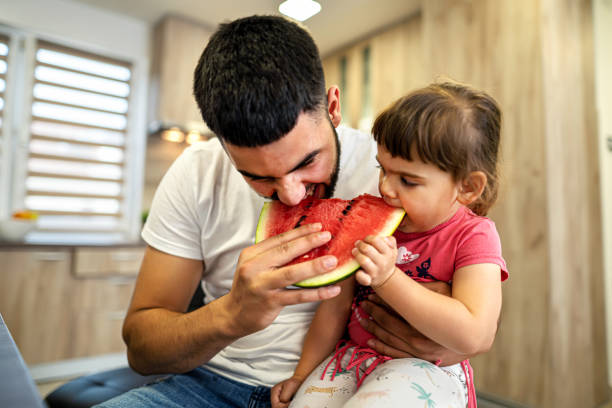 istock Young man with his little daughter eating watermelon 1324722183