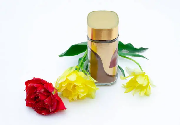 Photo of Instant coffee in a clear glass jar next to a yellow and red tulip. A layout for your product. Concept photography. Fragrant coffee and tulips on a white background.