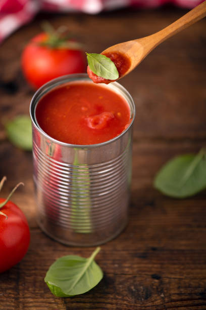 istock Open tin of tomatoes sauce with whole fresh tomatoes on a rustic wooden table 1324723093