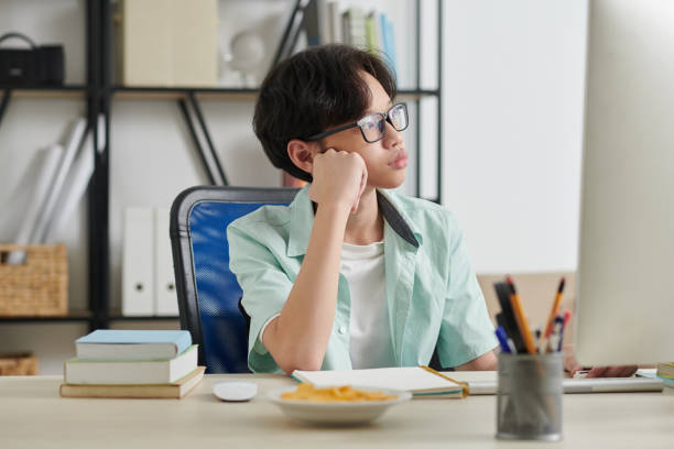 boring homework pictures Pensive Teenage Boy Sitting at Desk Portrait of dreamy pensive teenage boy sitting at desk at home and looking through window boring homework twelve stock pictures, royalty-free photos & images
