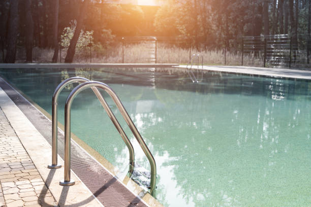 istock Big luxury empty rectangular swimming pool with clean blue water and ladder at tropical forest beach resort at sunrise morning light and nobody outdoors. Healthy leisure lifestyle travel and exercise 1324724905