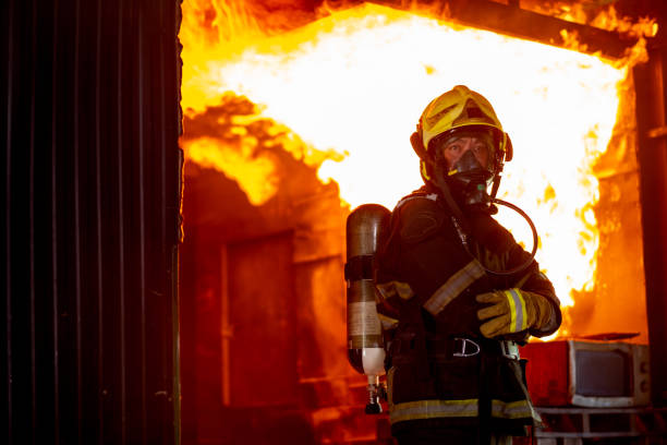 istock Fire on wall and ceiling in the kitchen behind firefighter man with protective and safety clothes stand with arm-crossed 1324725022