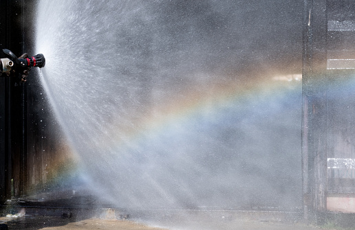 Close up water curtain from sprinkler of fire station with reflection of rainbow in front of area of fire occur.