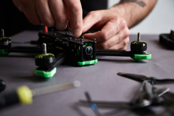 istock Close up of man's hands assembling a drone from parts, using tools, Preparing high-speed racing quadcopter for flight. Repair drone before training process. 1324725815