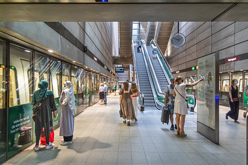 The subway station platform at T-Centralen in downtown Stockholm busy with passengers waiting as a train arrives in the station.