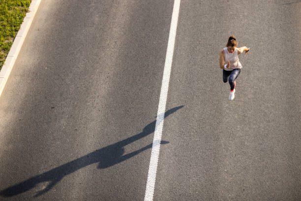 istock Young woman jogging on the road 1324729879